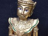 brass figurine of a person sitting on a black surface