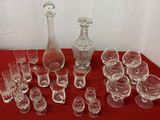 plusieurs verres et une carafe posés sur une table rouge