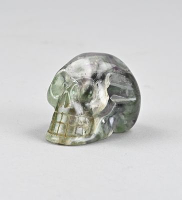 une image représentant un crâne de cristal vert et blanc posé sur une surface blanche