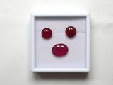 une boîte blanche contenant trois pierres précieuses rouges