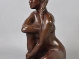 bronze statue of a woman sitting on her knees with her arms crossed