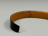 a close up of a black and tan leather belt on a white surface