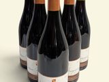 six bottles of wine are lined up in a row on a white surface