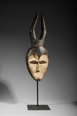 a wooden mask with horns on a stand