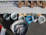 several buckets of screws and bolts are on the ground next to a pallet of wood