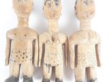 trois figurines en bois représentant trois hommes debout côte à côte sur une surface blanche