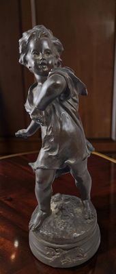 une statue représentant un garçon tenant un oiseau sur une table