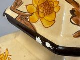 a vase with flowers painted on it sitting on a table