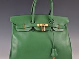 un sac à main en cuir vert avec des finitions dorées sur la poignée