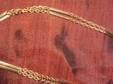 une photo d'un collier plaqué or posé sur un tissu rouge