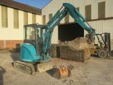 a blue excavator that is sitting in front of a building