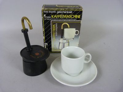 une tasse et une soucoupe blanches posées à côté d'une boîte de café