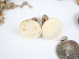 a silver coin sitting next to a pair of silver ear plugs