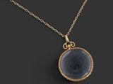 un collier plaqué or avec un pendentif en pierre noire monté sur une chaîne