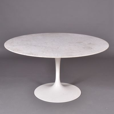 une table en marbre blanc avec un piètement circulaire sur fond gris