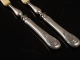 two silverware spoons and a knife on a black table