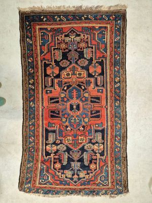 un vieux tapis est posé par terre à côté d'une plante en pot