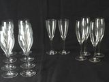 six verres à vin transparents alignés sur un fond noir
