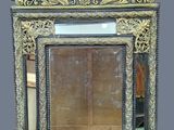an ornately carved mirror with a gold frame on a gray background