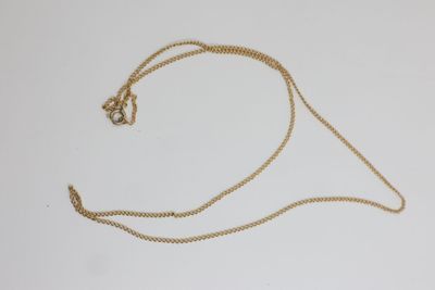 gros plan d'un collier en or avec une chaîne sur une surface blanche