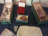 trois boîtes de bijoux posées sur une table, à côté d'un sac à main