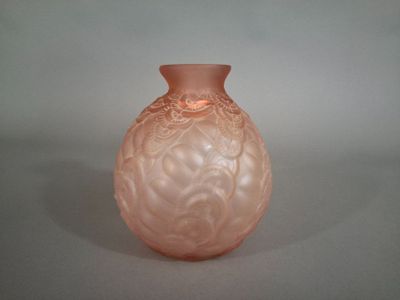 un vase en verre rose posé sur une surface blanche