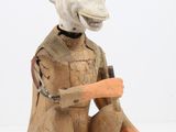 une statue représentant un singe tenant une carotte dans la main