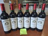 six bouteilles de vin rouge sont alignées sur une table