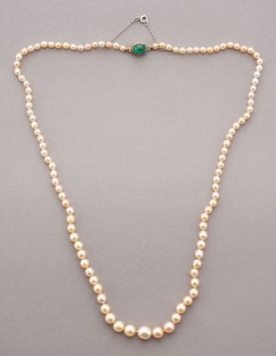 un collier de perles blanches muni d'un fermoir orné d'une pierre verte