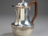 an antique silver coffee pot with a wooden handle on a grey background