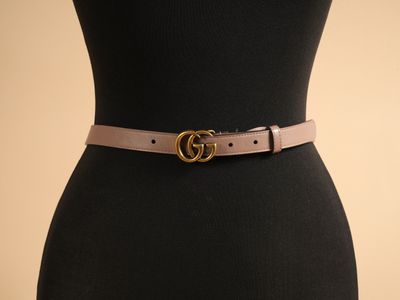 un torse de mannequin noir avec une ceinture marron et une boucle dorée