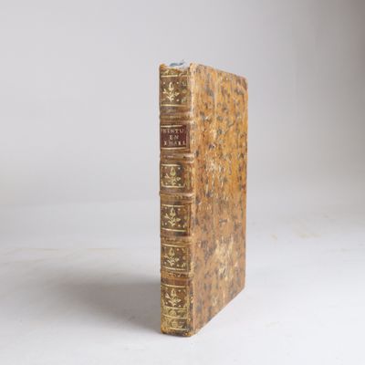 un vieux livre posé sur une table blanche à côté d'un mur blanc
