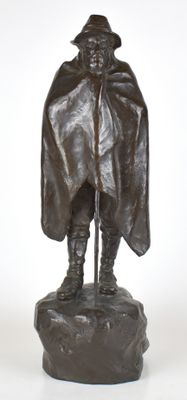statue en bronze représentant un homme vêtu d'une cape et coiffé d'un chapeau, assis sur un rocher
