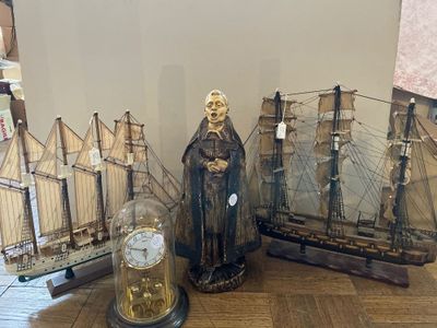 une statue représentant un homme debout à côté d'un bateau et d'une horloge