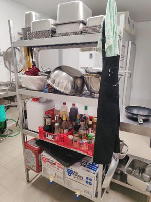 une étagère métallique avec des casseroles et des poêles dans une cuisine