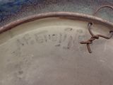 a metal bowl with a rusted handle and writing on it