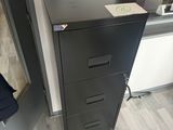 a black filing cabinet in the corner of a room