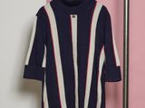a sweater hanging on a rack in front of a pink and white wall