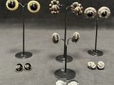 several pairs of earrings are displayed on a stand on a gray surface