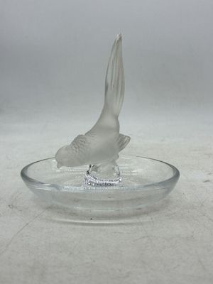 un oiseau en verre posé sur une assiette en verre