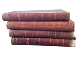 several old books stacked on top of each other on a white surface