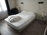 un lit avec une couette blanche et une chaise noire dans un coin