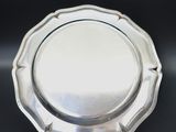 a close up of a silver plate on a black surface