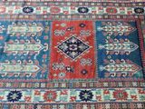 a close up of a blue and red oriental rug on a wooden floor