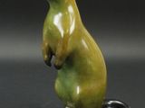 une statue verte et noire représentant une belette, posée sur un socle noir