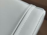 a close up of a white leather couch with a pillow