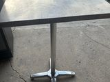 une table avec un plateau carré et un piètement en métal
