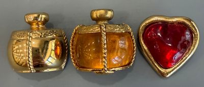 trois flacons de parfum en verre doré et rouge posés sur une table