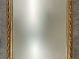 un miroir à cadre doré sur un mur gris avec un mur blanc