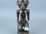 une image représentant une statue en bois d'un chat portant une étiquette sur la poitrine
